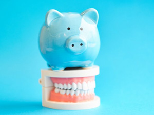 Blue piggy bank on top of a dental model