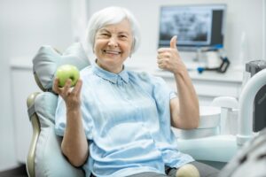 Woman holding apple is happy with her implants