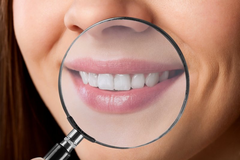 A magnifying glass set over a woman’s smile